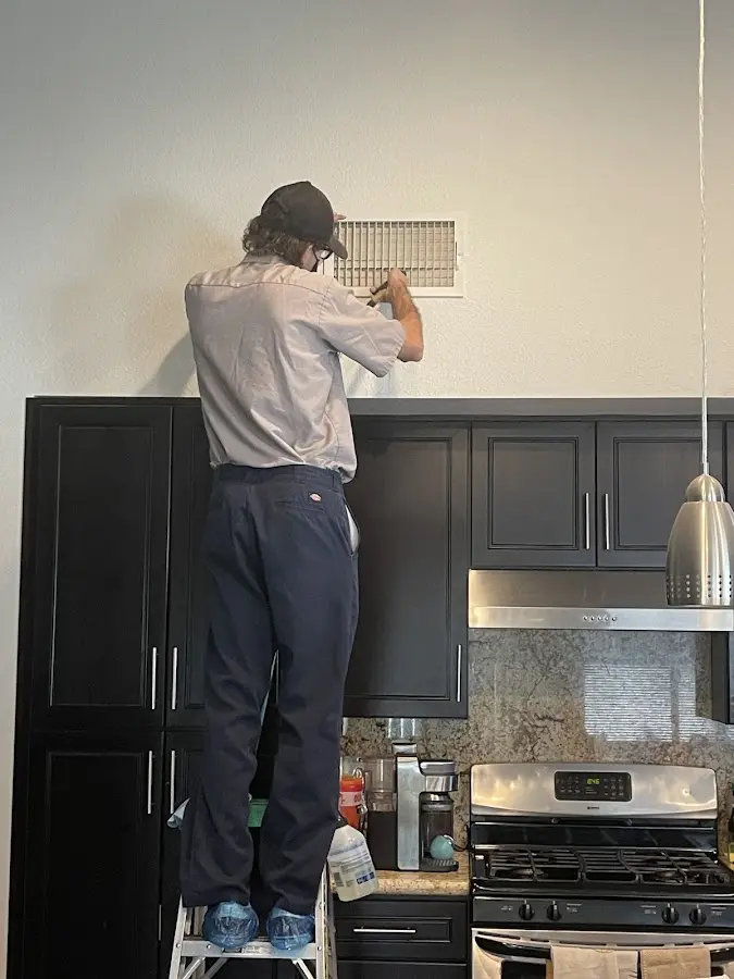 Technician inspecting an air vent during HVAC service in Goddard